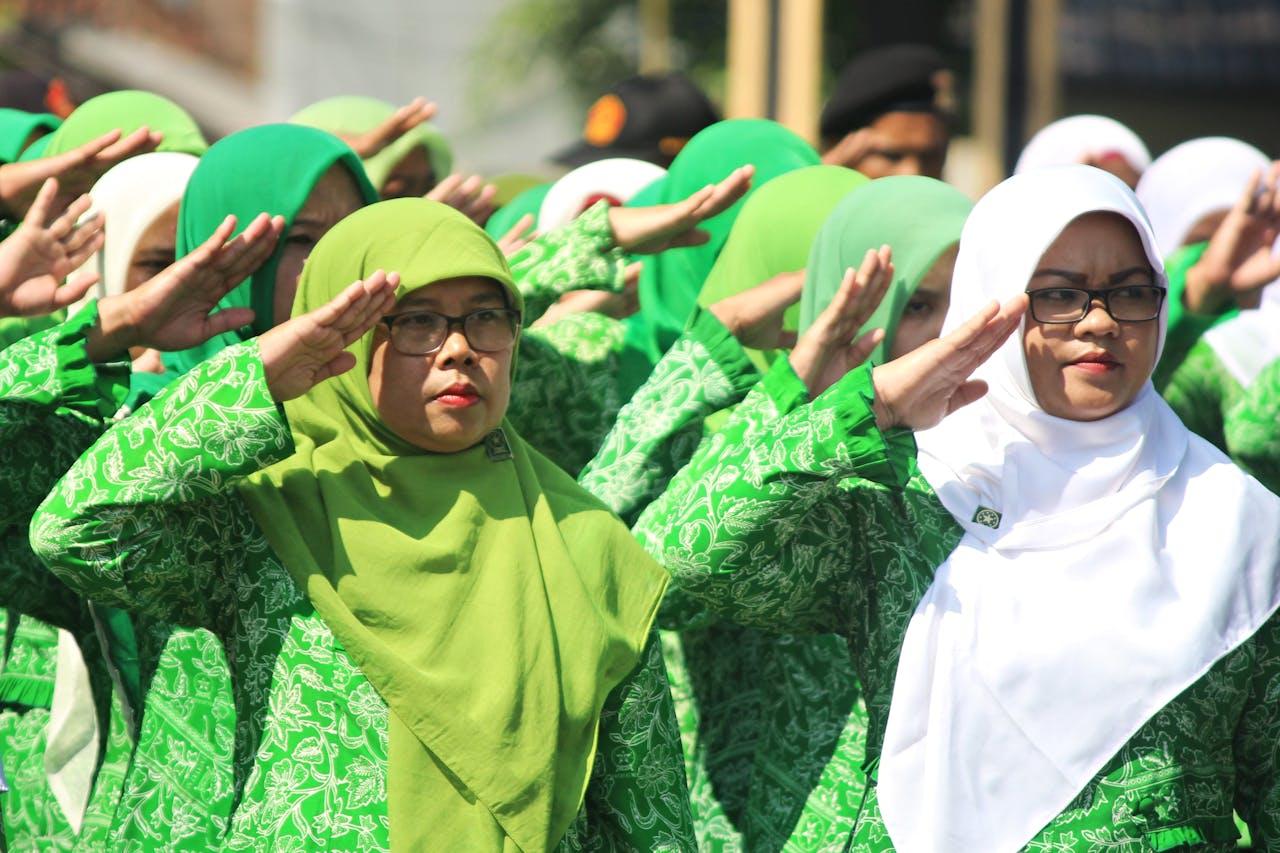 services-01 Indonesian women in hijabs salute at an outdoor ceremony in Central Java.